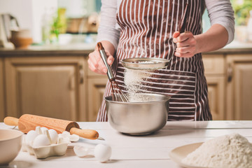 Young woman holding bowl with dough and whisk, closeup