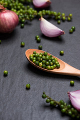 Fresh vegetables on black table. Red onion rings and green peppercorns. Top view.