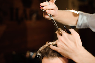 Master cuts hair and beard of men in the barbershop