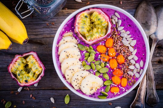 Blueberry smoothies bowl with sea-buckthorn, banana, passion fruit, chia seeds, pumpkin seeds, sunflower and flax seeds