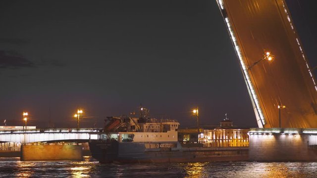 Timelapse in night. Barges, cargo ships floats through a drawbridge along the Neva River in Saint Petersburg.
