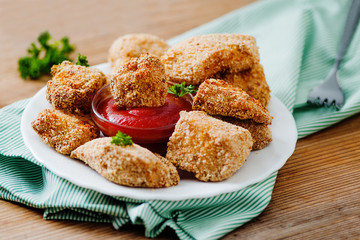 Chicken nuggets on the white plate with tomato sauce