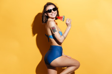 Cheerful young lady in swimwear eating candy.