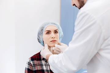 Serious young woman having an appointment with a plastic surgeon