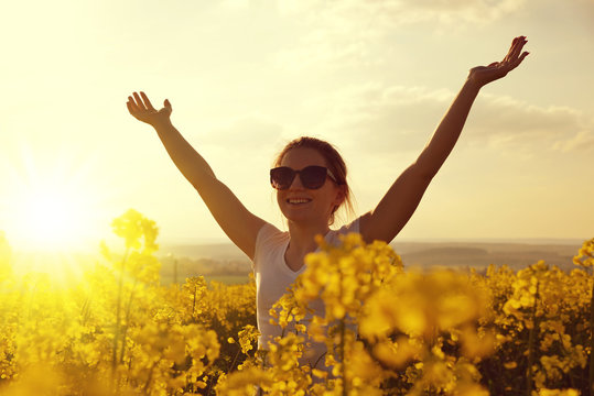 Young happy woman in the rapeseed field at sunset.