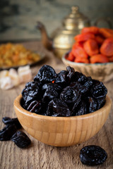 Prunes in a bamboo bowl on an old wooden background. Healthy dried fruit. Selective focus.