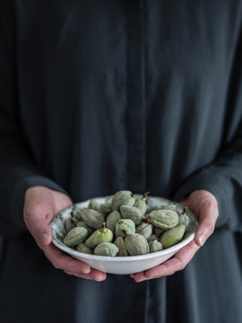 Midsection of woman holding bowl of green almonds