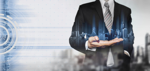 Businessman holding blue hologram of modern buildings, innovation technology concept