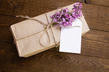 Bouquet of lilacs on a wooden table with a gift box
