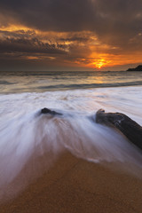 Beautiful pattern of waves surrounding a dead wood at the beach. The moment captured in long exposure.