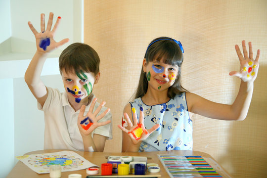 Children paints faces with colors. Joyful children with paints on their faces. Creativity and education concept. Children paints faces with colors. 
