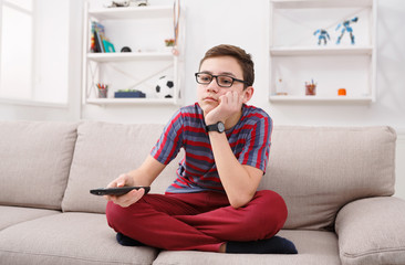 Bored teenage boy watching tv at home © Prostock-studio