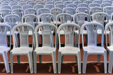 Rows of white folding chairs on lawn before a graduation ceremony in summer time