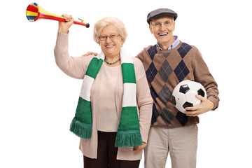 Cheerful elderly soccer fans with a trumpet and a football