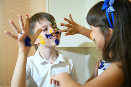 Joyful children with paints on their faces. Creativity and education concept. Children paints faces with colors. 