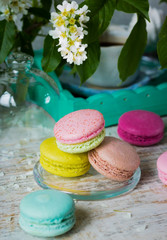 Different macaroons on a light wooden background and bird-cherry branches