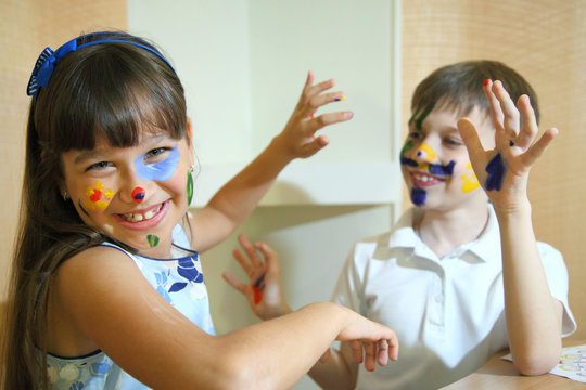 Joyful children with paints on their faces. Children paints faces with colors. 