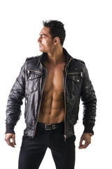 Fototapeta premium Handsome muscle man wearing leather jacket on naked torso, isolated on white background looking to a side
