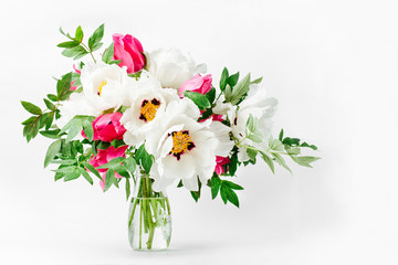 Beautiful bouquet of white peonies and pink tulips in a glass vase on a white background