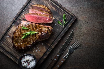 Keuken foto achterwand Steakhouse Gegrilde biefstuk op een houten bord. Bovenaanzicht kopie ruimte.