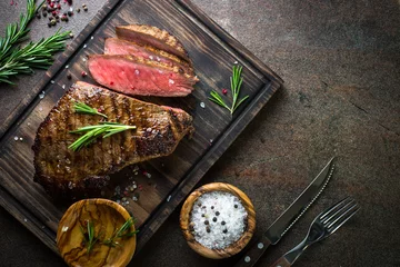 Photo sur Plexiglas Steakhouse Steak de boeuf grillé sur planche de bois. Espace de copie vue de dessus.