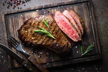 Photo sur Plexiglas Viande Steak de boeuf grillé sur planche de bois. Vue de dessus.