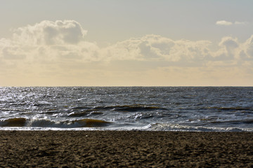 Fototapeta na wymiar The beach of northern sea with waves splashing at the shore