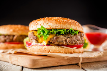 Classic american hamburger with beef and tomato sauce on dark background.