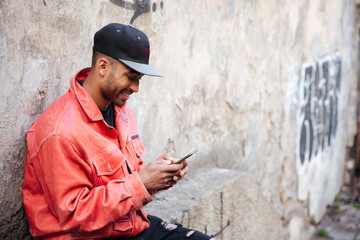 Afro american man in hat typing message on mobile phone