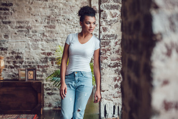 Beautiful african girl in white t-shirt standing at home.