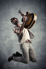 adult caucasian guitarist portrait playing electric guitar and jumping on grunge background. Music singer modern concept