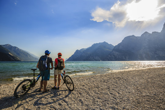 Mountain biking, couple with bikes on Lake Garda, Riva del Garda, Italy