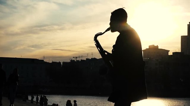 Street musician play saxophone sunset silhouette
