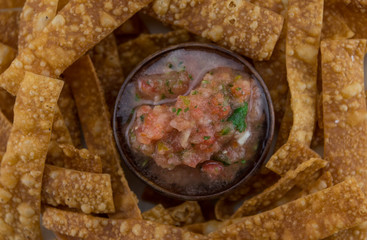 Small Bowl of Salsa Surrounded by Homemade Chips
