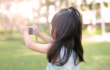 Child girl taking pictures on camera in the garden, Focus at child.