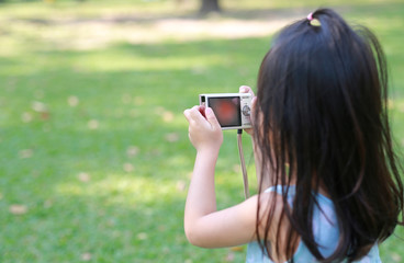 Child girl taking pictures on camera in the garden.
