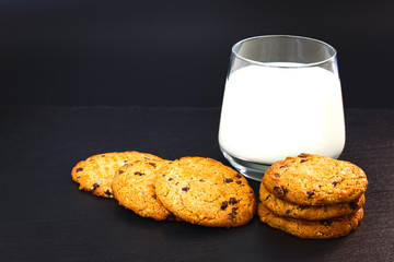 cookies and a glass of milk on black background 