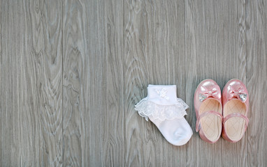 Girl's small shoes with white socks on wood.