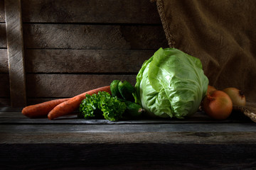 still life with vegetables. cabbage, carrots, onions, cucumbers, parsley on wooden background with beautiful sun