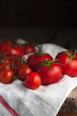 .Ripe tomatoes on a branch of a white napkin, dark background.