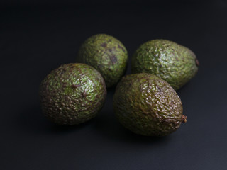 Ripe brown and dark green avocados isolated on black background