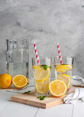 Fresh citrus lemonade in the glasses,concrete grey background, place for text.