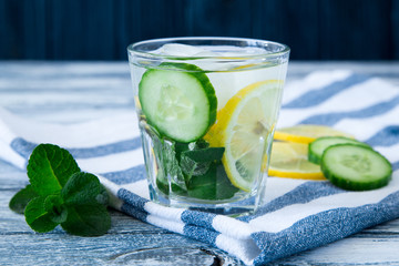 Lemon and cucumber detox water on blue colored wooden background.