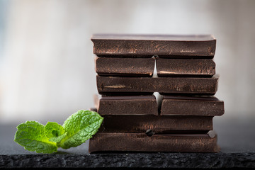 Stack of chocolate slices with mint leaf. dark chocolate over wooden background, selective focus