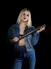 Criminal young woman with baseball bat, young hooligan in jeans and a denim jacket