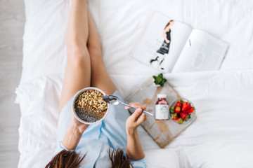 Young woman eating healthy breakfast in bed 