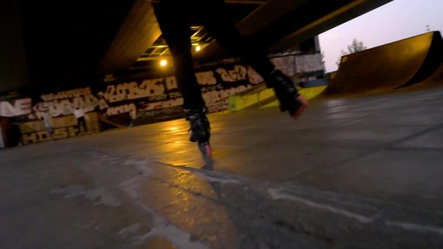 Legs of inline skater, slow-mo. Rollerblader in skatepark. Home of extreme sport.