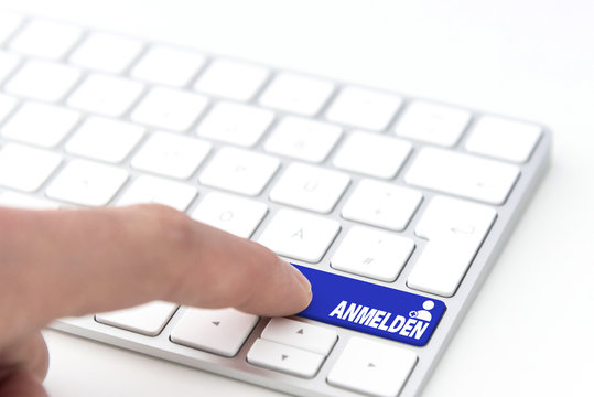 finger pressing a blue key labeled ANMELDEN (German for register) with symbol on a computer keyboard concept