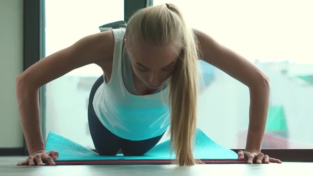 Beautiful athlete blonde wringing out hard against the window in gym close-up.
