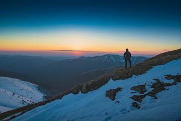 Hiker stands on a hill and look to the horizon